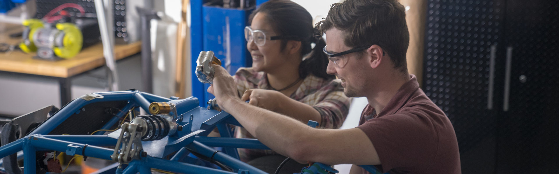 Male and female students working on a mechanical project in an engineering lab
