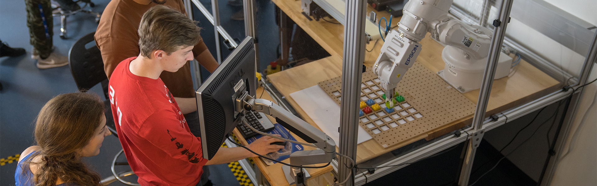 Students working with a robotic arm in a mechatronics lab
