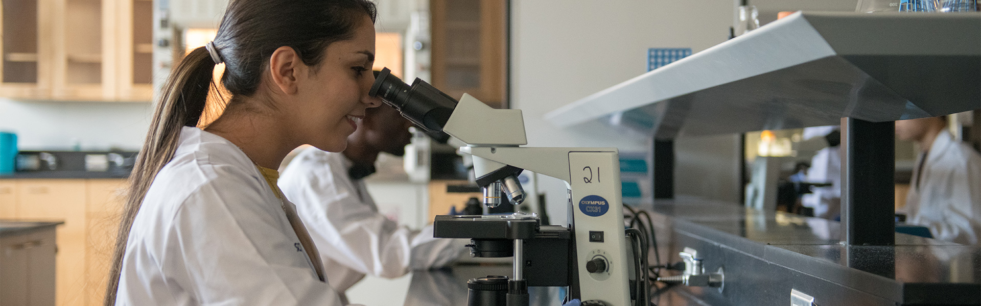 Student observing a specimen under a microscope